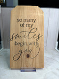 RJ Custom Works natural wood sign with engraved Christian quote "so many of my smiles begin with you" in script font.